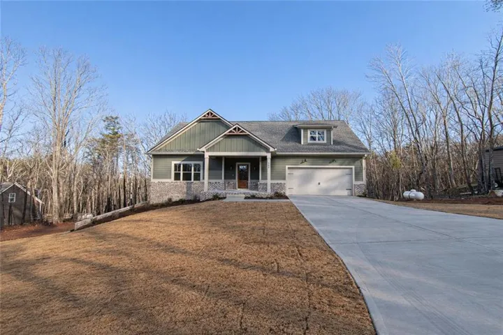 Craftsman-style exterior with green siding, a stone facade, and a covered front porch