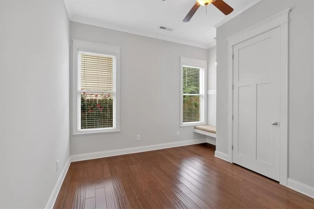 Unfurnished bedroom with dark wood finished floors, ornamental molding, and a ceiling fan