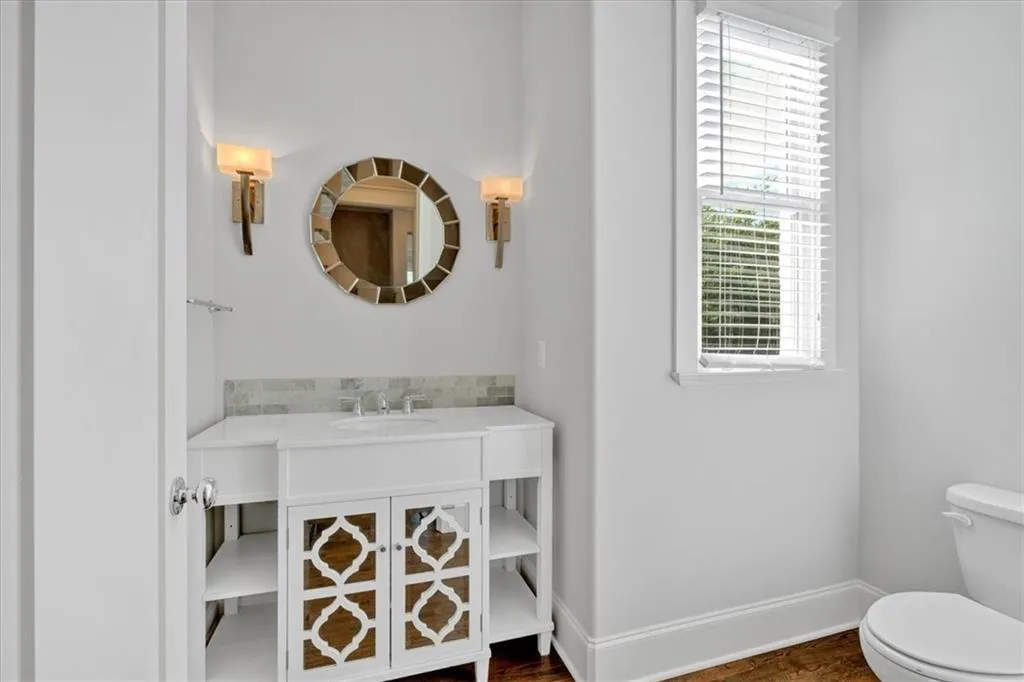 Half bathroom with vanity, wood finished floors, and tasteful backsplash