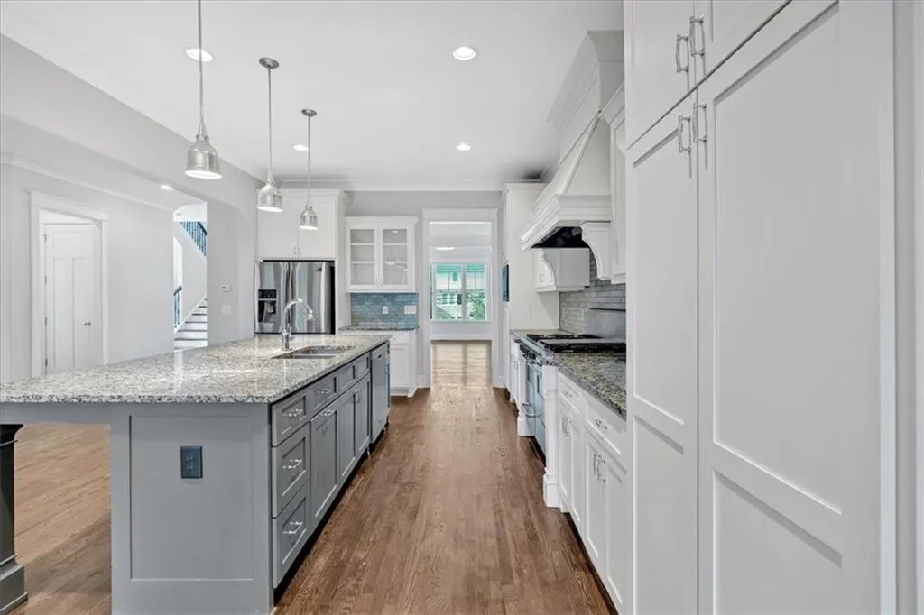 Kitchen with gray cabinetry, appliances with stainless steel finishes, tasteful backsplash, white cabinetry, and dark wood-style floors
