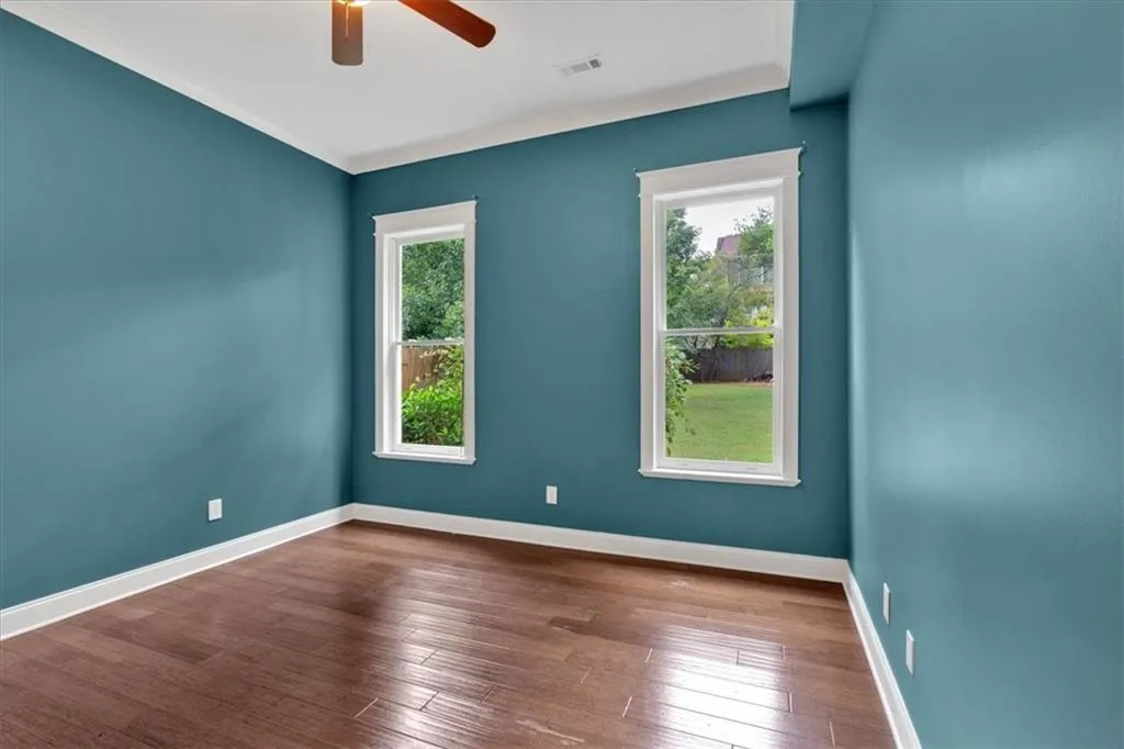 Spare room with healthy amount of natural light, a ceiling fan, and hardwood / wood-style floors