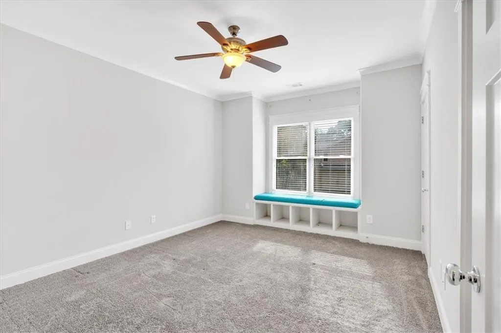 Unfurnished room with crown molding, carpet, and a ceiling fan