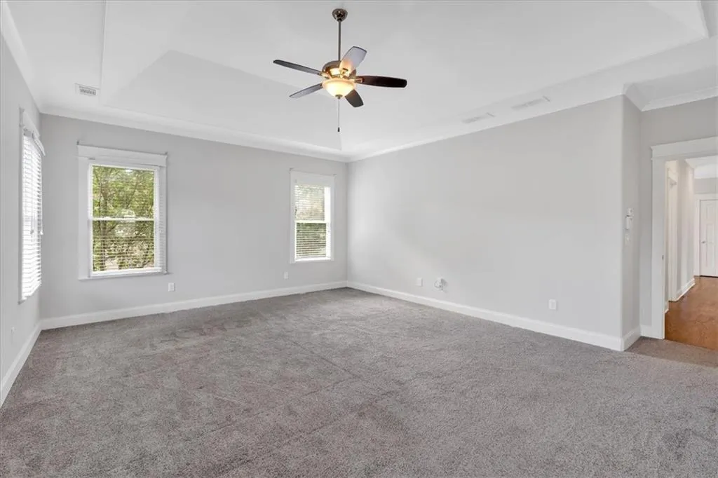 Unfurnished room with a tray ceiling, carpet floors, a ceiling fan, and crown molding