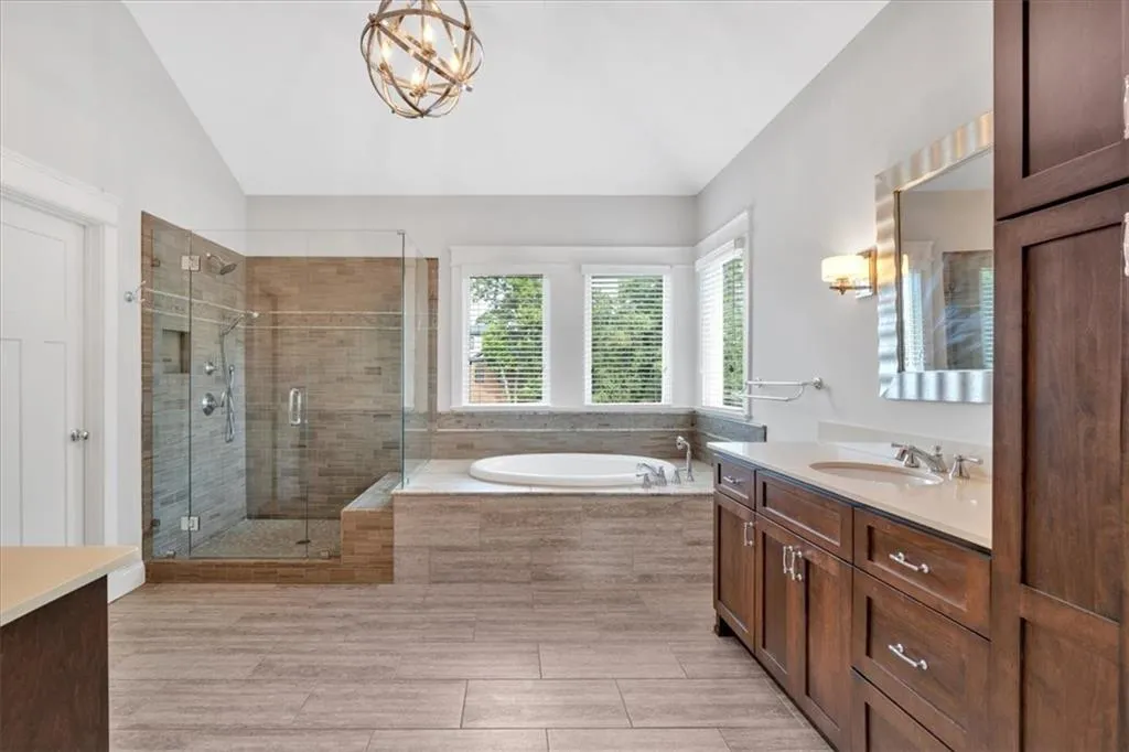 Full bathroom featuring vaulted ceiling, vanity, a bath, and a stall shower