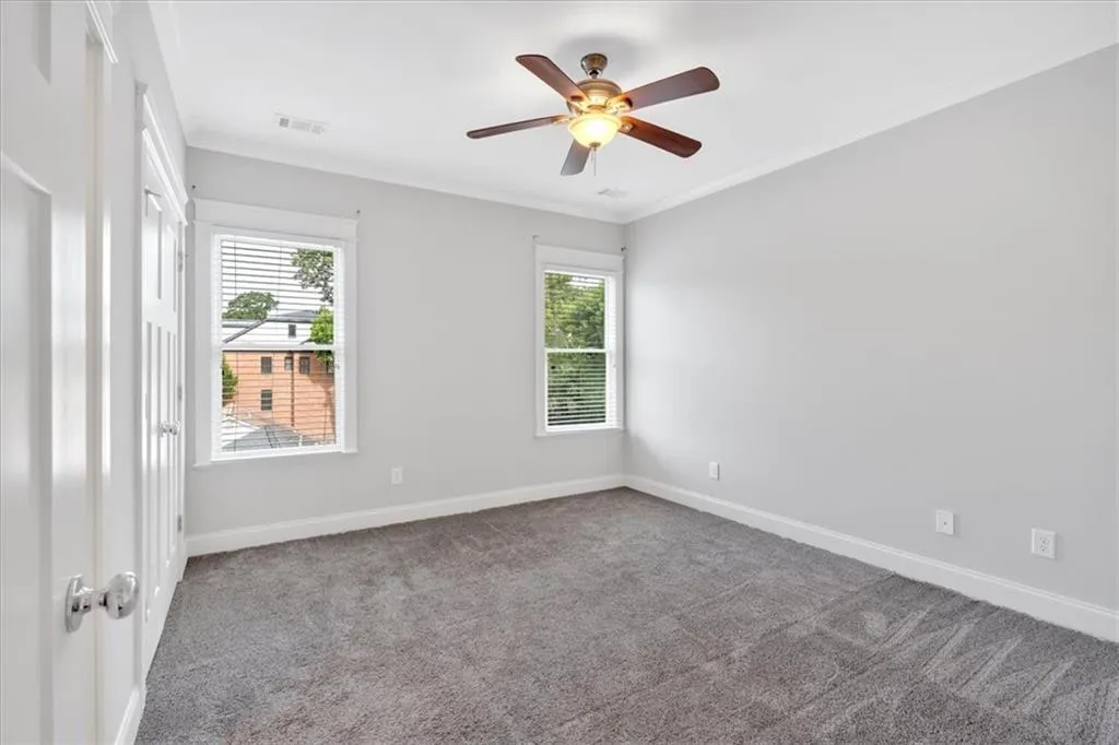 Unfurnished room featuring plenty of natural light, carpet, a ceiling fan, and crown molding