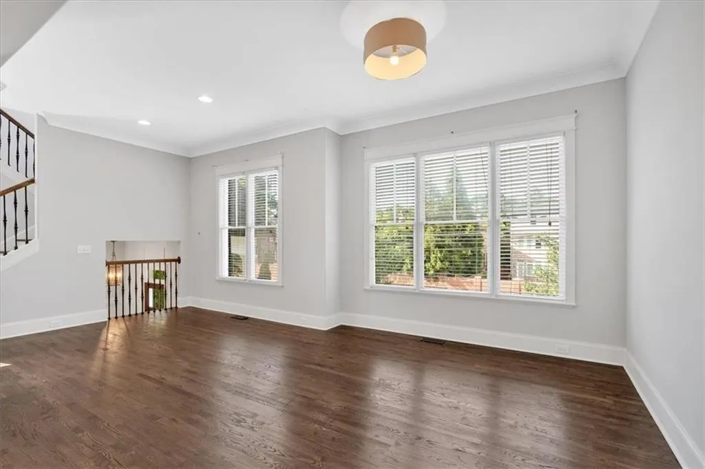 Unfurnished living room featuring stairway, wood finished floors, ornamental molding, and recessed lighting