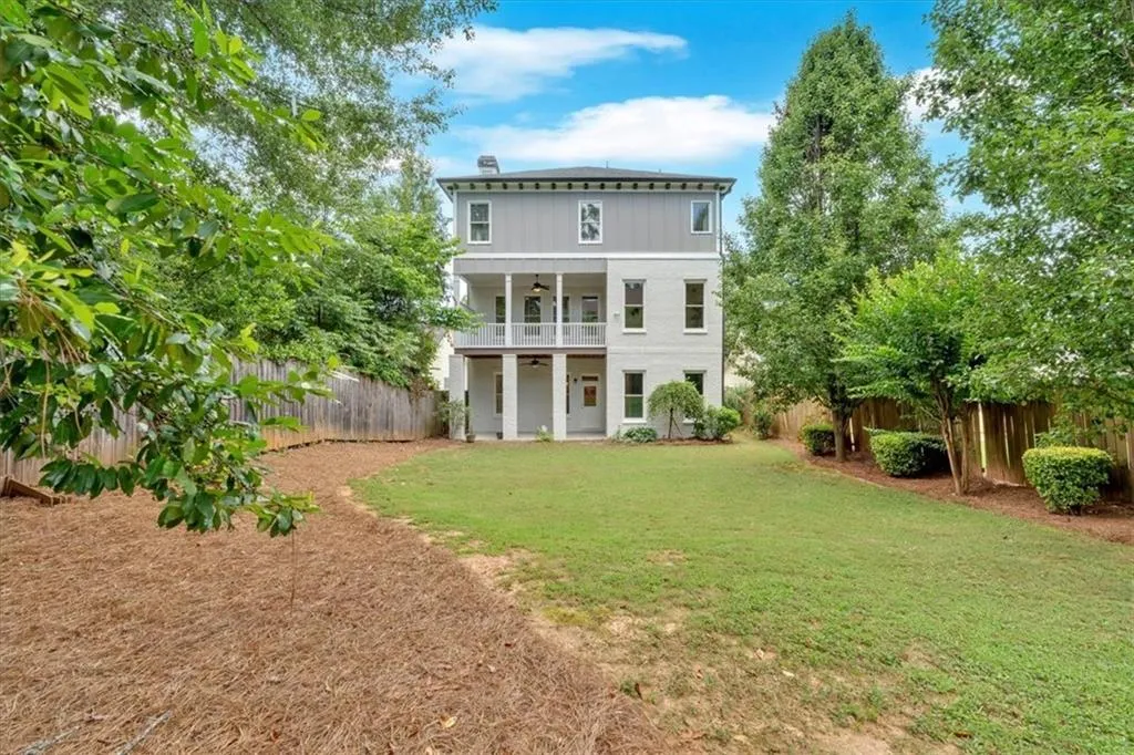 Rear view of house featuring ceiling fan, a fenced backyard, and a balcony