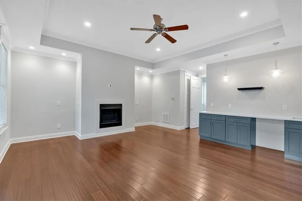 Unfurnished living room with ceiling fan, a fireplace, wood finished floors, recessed lighting, and crown molding