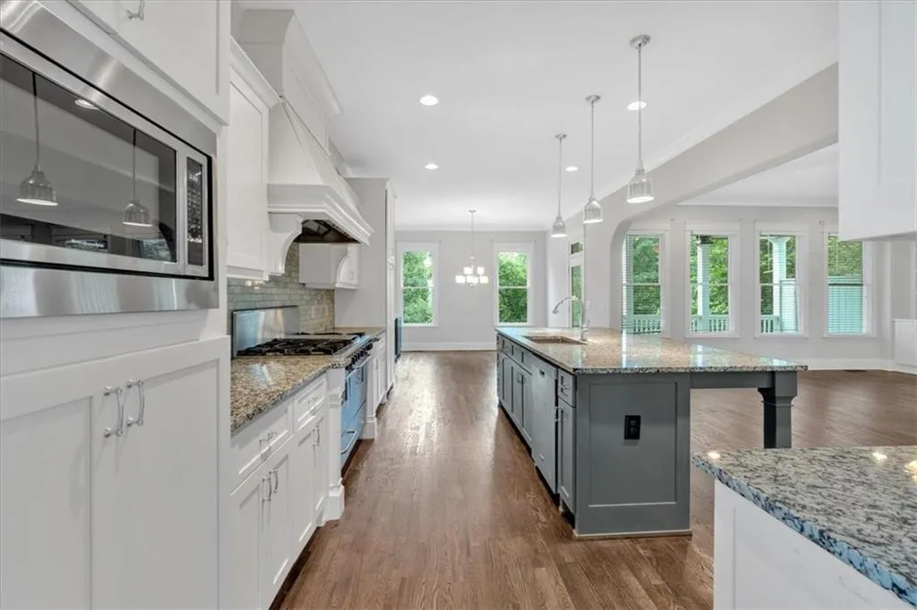 Kitchen with stainless steel appliances, white cabinets, backsplash, dark wood-type flooring, and recessed lighting