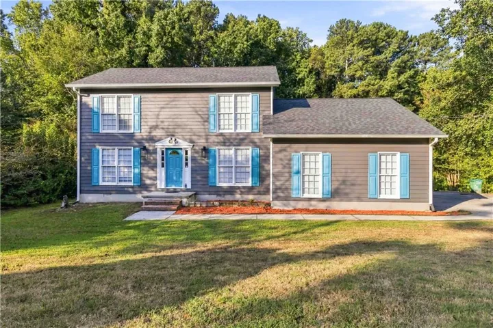 Two-story exterior with gray siding, contrasting blue shutters, a blue entry door, and a shingle roof