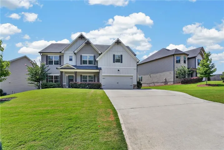 Two-story residence featuring a covered entry, attached garage, and a concrete driveway
