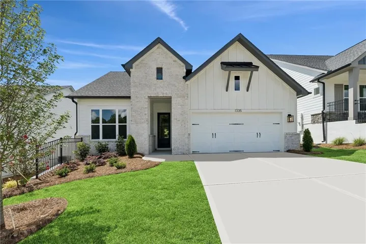 White brick and board-and-batten exterior with dark trim accents, a two-car garage, and a concrete driveway