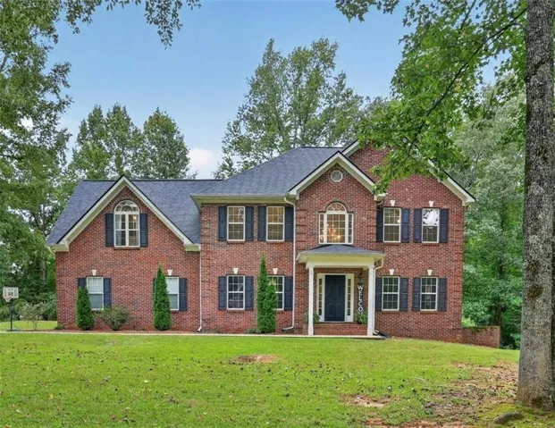 Brick exterior construction featuring a covered entry, dark-paneled door, and multiple windows with dark shutters