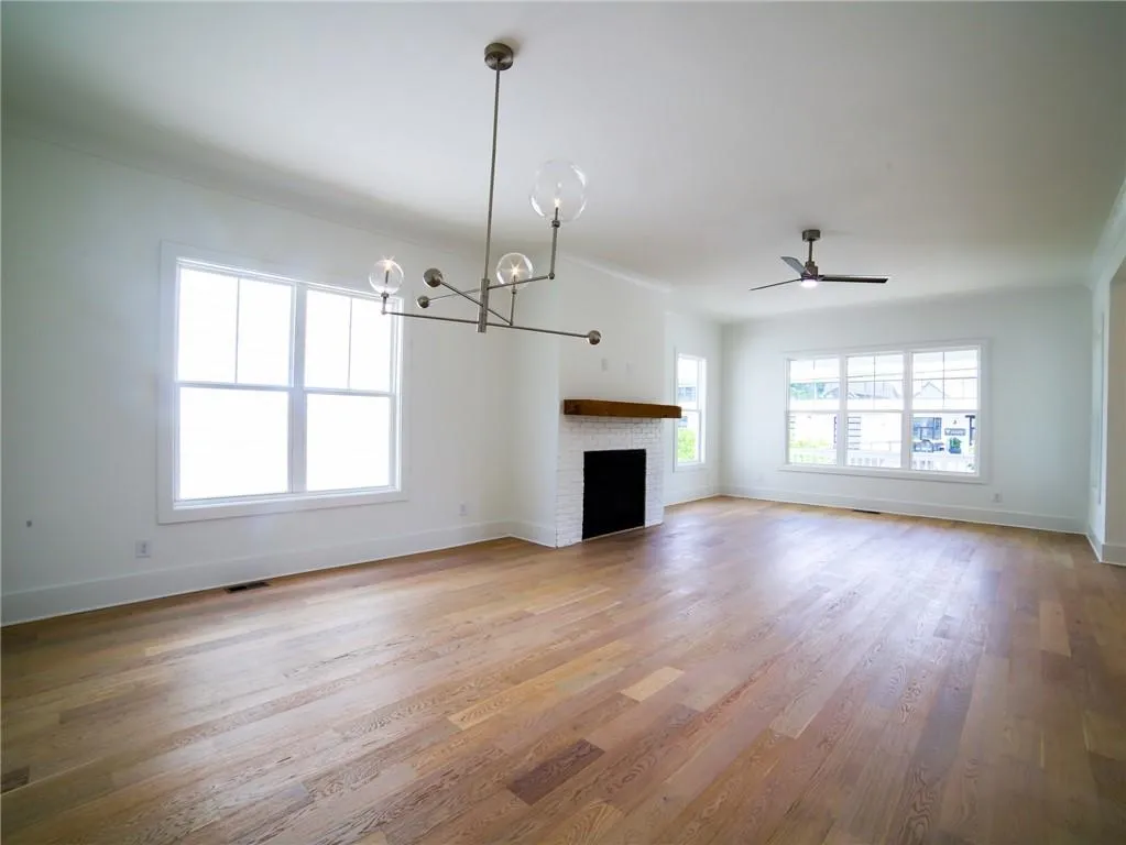Unfurnished living room featuring baseboards, light wood-style flooring, a chandelier, and ceiling fan
