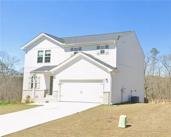 Two-story residence featuring white siding, a two-car garage, and a concrete driveway