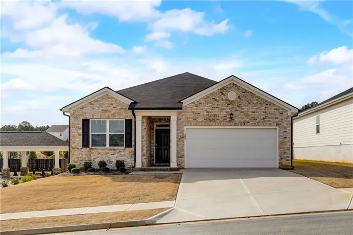 View of front of home with concrete driveway, a garage, brick siding, and roof with shingles