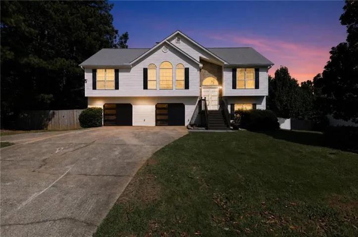 Split-level residence featuring a two-car garage with contemporary doors, a front porch with dark wood stairs, and a well-maintained lawn