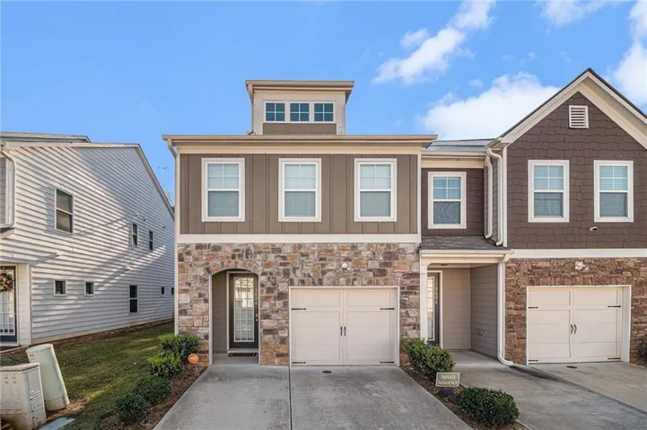 Stone veneer facade, two-car garage, upper-level dormer windows, low-maintenance landscaping, and a covered entry