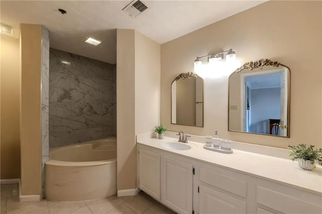 Full bathroom featuring a tub with marble appearance, a marble finish shower, vanity, a textured ceiling, and tile patterned flooring