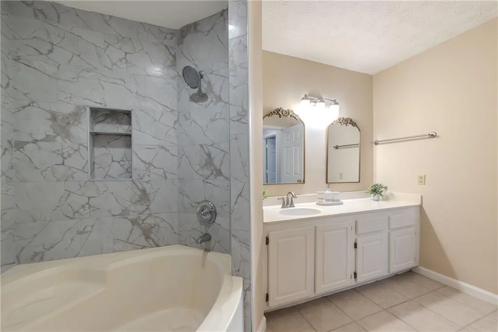 Bathroom featuring vanity, a textured ceiling, tile patterned floors, and tub / shower combination