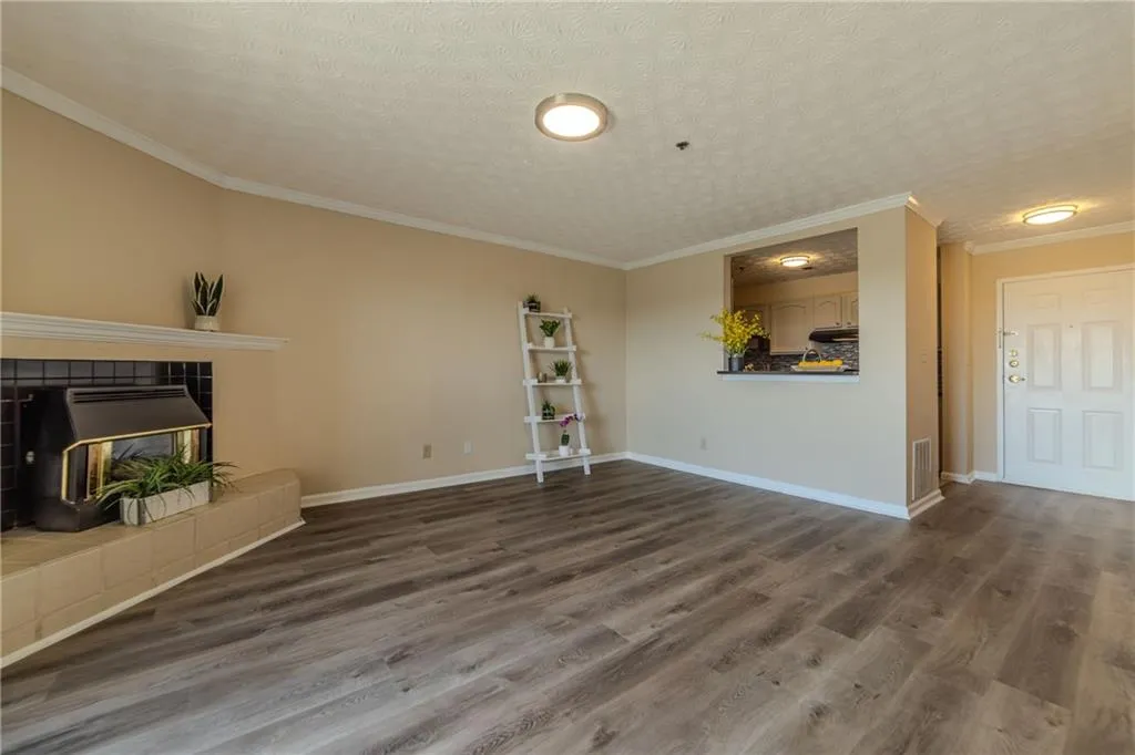 Unfurnished living room with crown molding, wood finished floors, and a textured ceiling