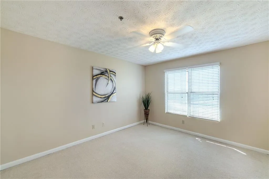 Spare room with carpet floors, ceiling fan, and a textured ceiling