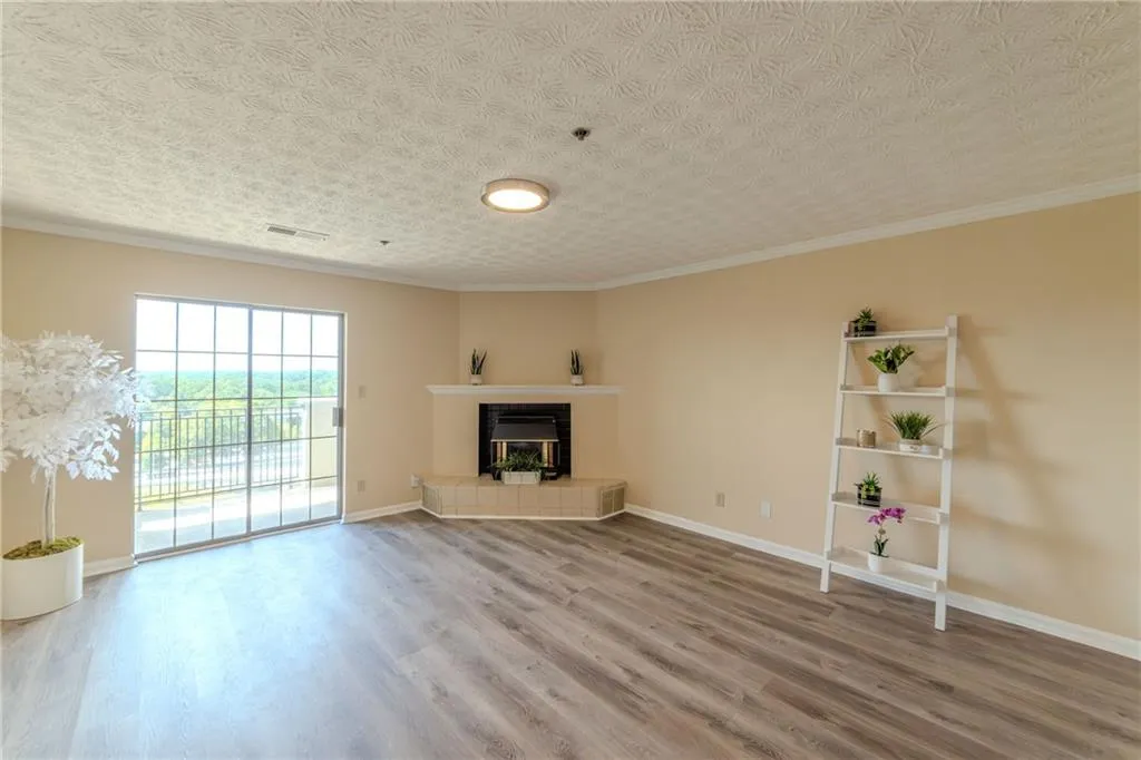 Unfurnished living room with wood finished floors, ornamental molding, a fireplace, and a textured ceiling