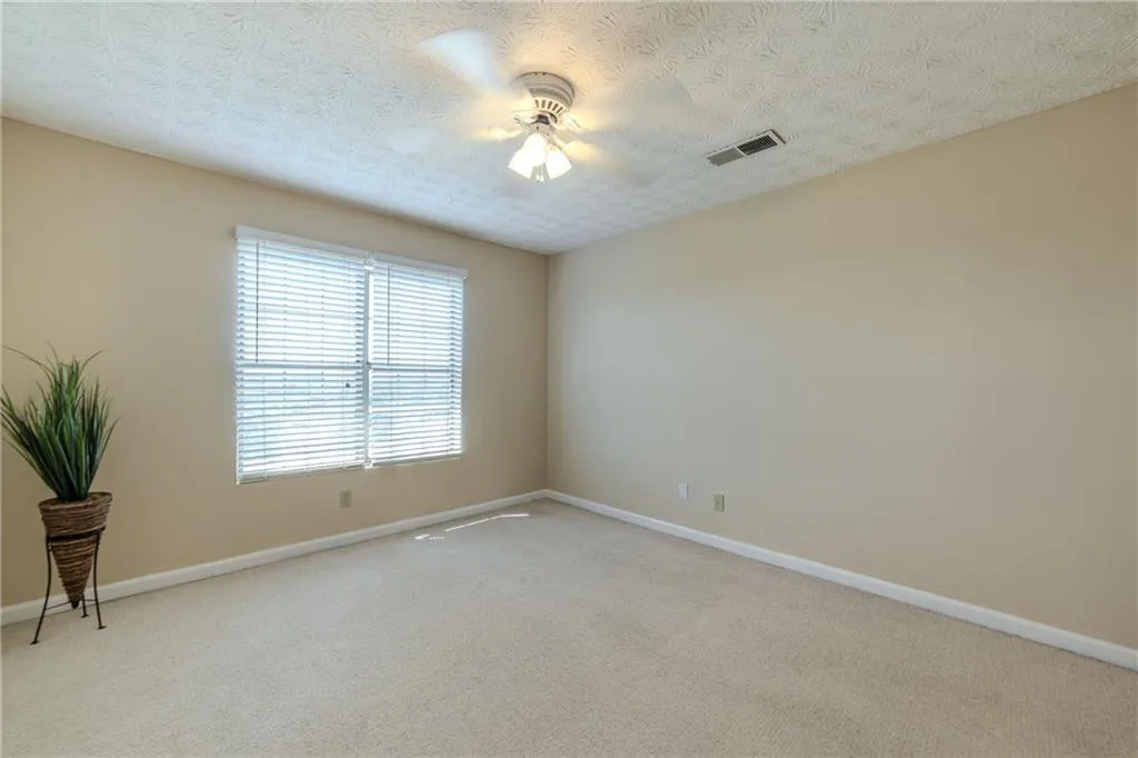 Unfurnished room with light carpet, ceiling fan, and a textured ceiling