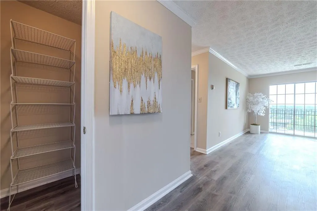Hallway with a textured ceiling, wood finished floors, and ornamental molding
