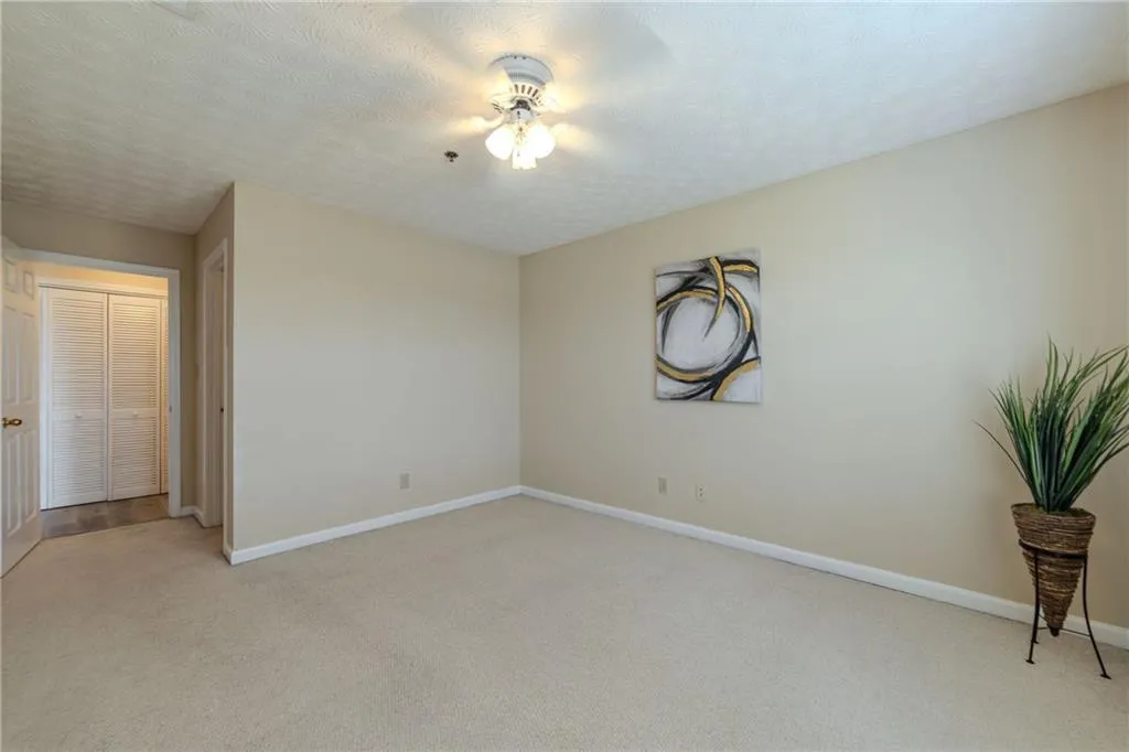 Spare room featuring light colored carpet, a textured ceiling, and ceiling fan
