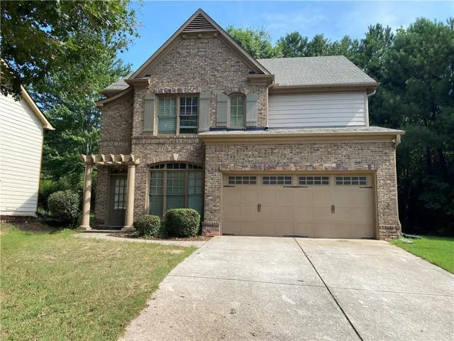 Brick facade with stone accents, two-car garage, front entry with pergola, arched windows, and decorative shutters
