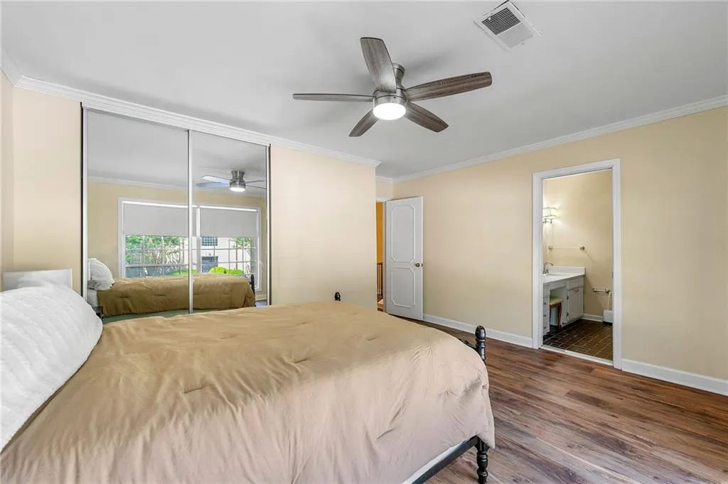 Bedroom with a closet, ornamental molding, visible vents, wood finished floors, and baseboards