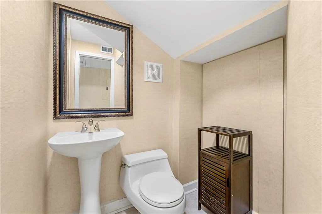 Bathroom featuring toilet, a sink, lofted ceiling, and visible vents
