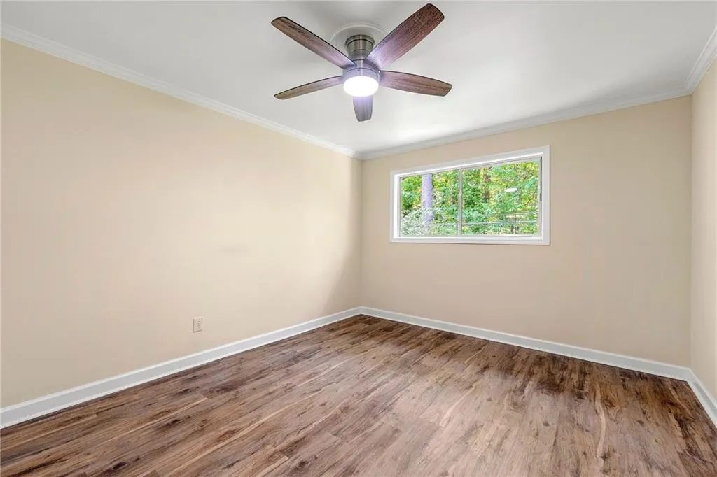 Unfurnished room featuring crown molding, baseboards, ceiling fan, and wood finished floors