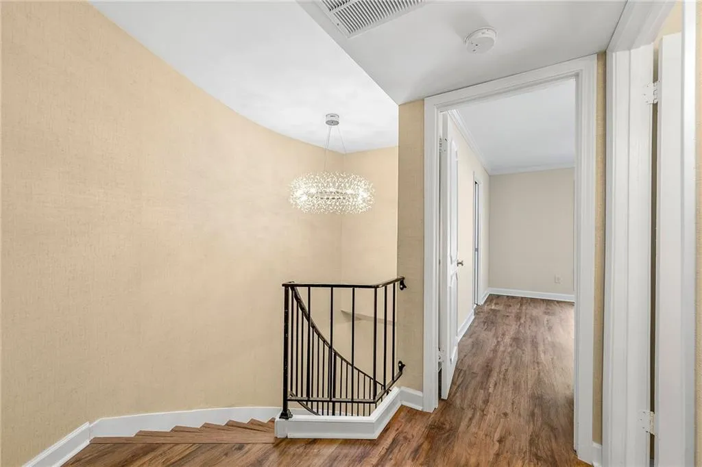 Corridor with visible vents, wood finished floors, an upstairs landing, baseboards, and a notable chandelier