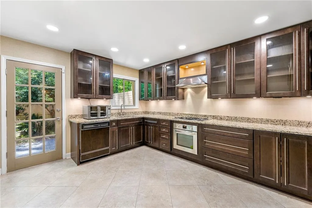 Bar with recessed lighting, under cabinet range hood, light tile patterned flooring, a sink, and stainless steel appliances