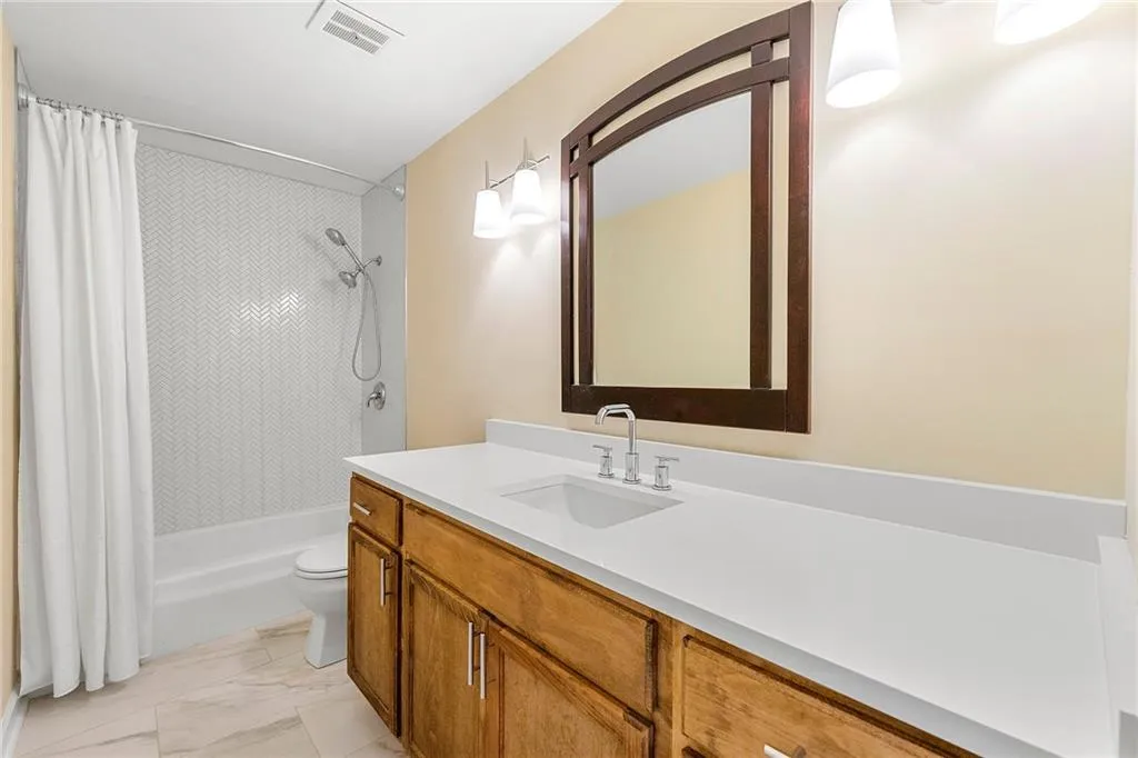 Bathroom with vanity, visible vents, toilet, shower / bath combo, and marble finish floor