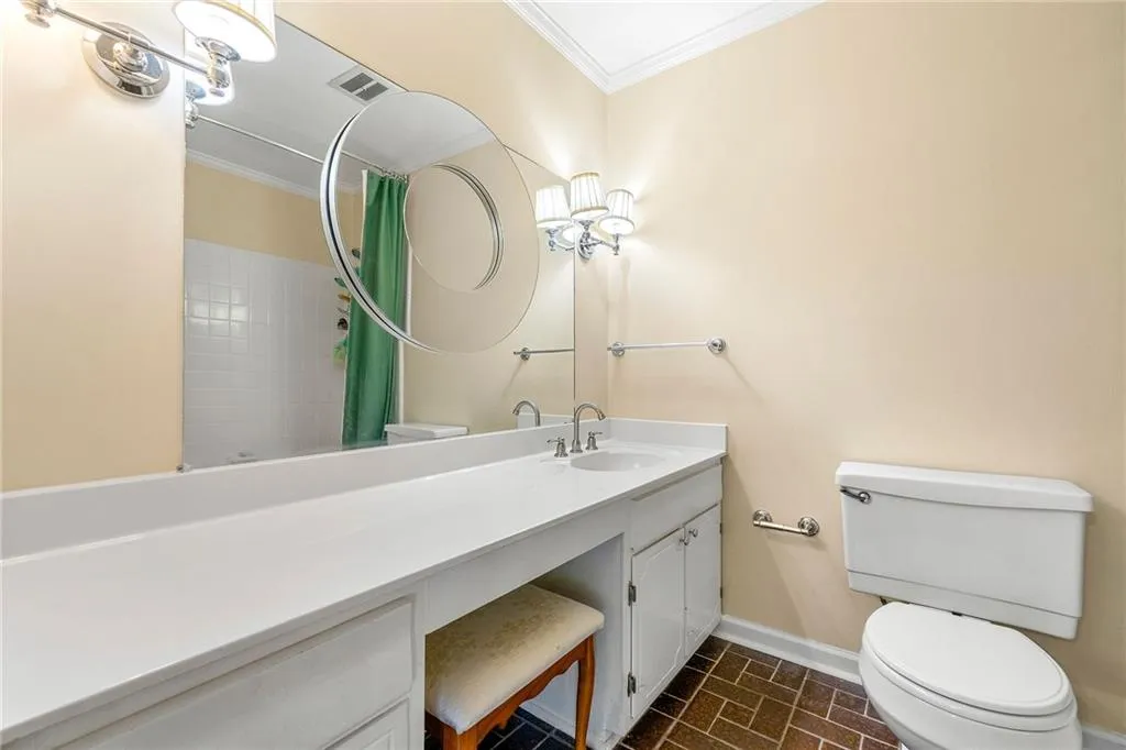 Full bath featuring vanity, ornamental molding, visible vents, toilet, and baseboards