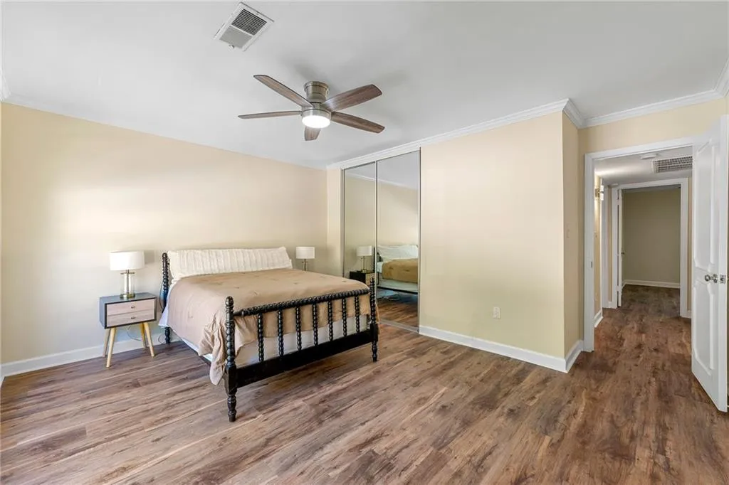 Bedroom with baseboards, a closet, crown molding, visible vents, and wood finished floors