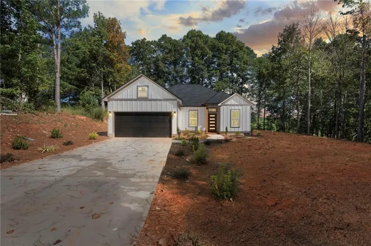 Single-story residence featuring board and batten siding, dark shingle roof, and an attached two-car garage