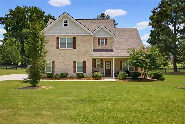 Two-story brick exterior featuring a covered front porch, gabled rooflines, and a paved driveway