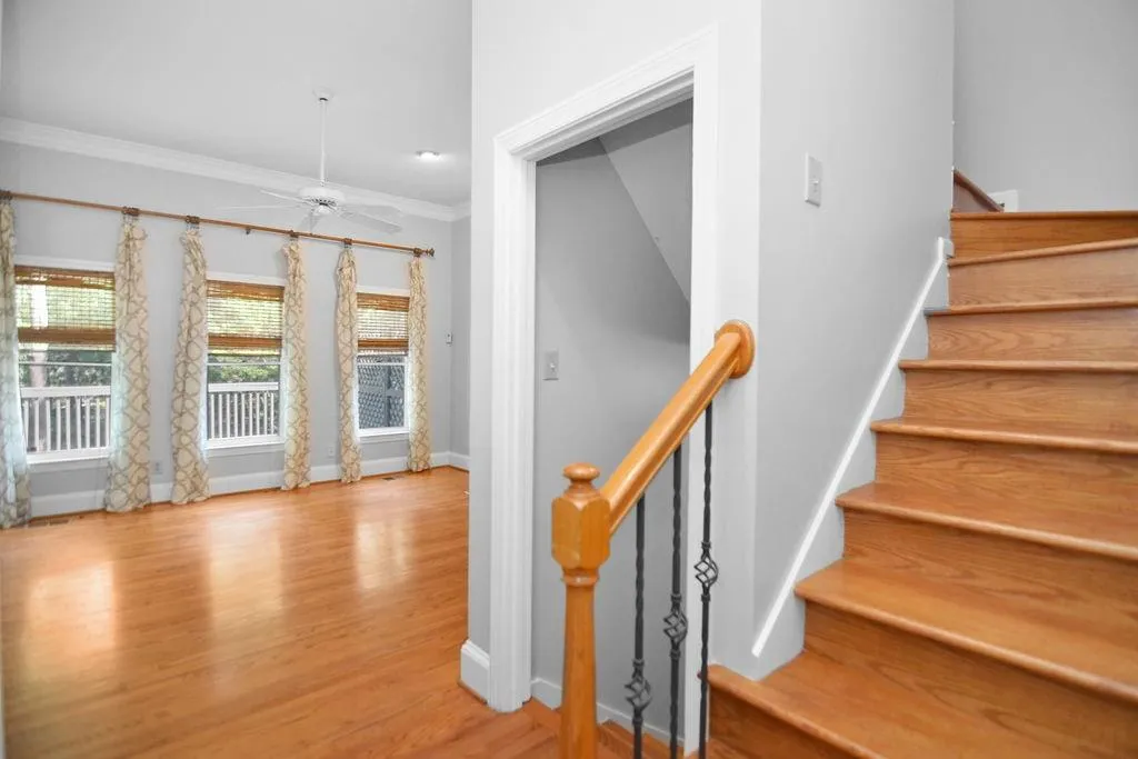 Stairs featuring crown molding, hardwood finished floors, with view to family room from foyer