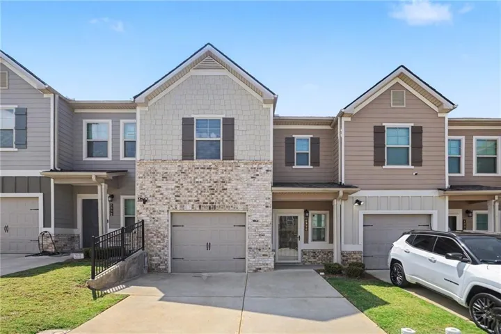 Multi-level townhome with brick and siding exterior, attached garage, and a covered entry