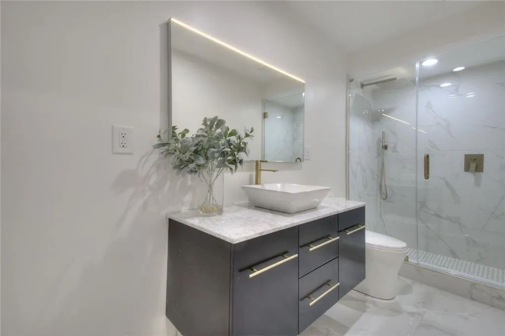 Full bathroom with vanity, light marble finish floors, a marble finish shower, and recessed lighting