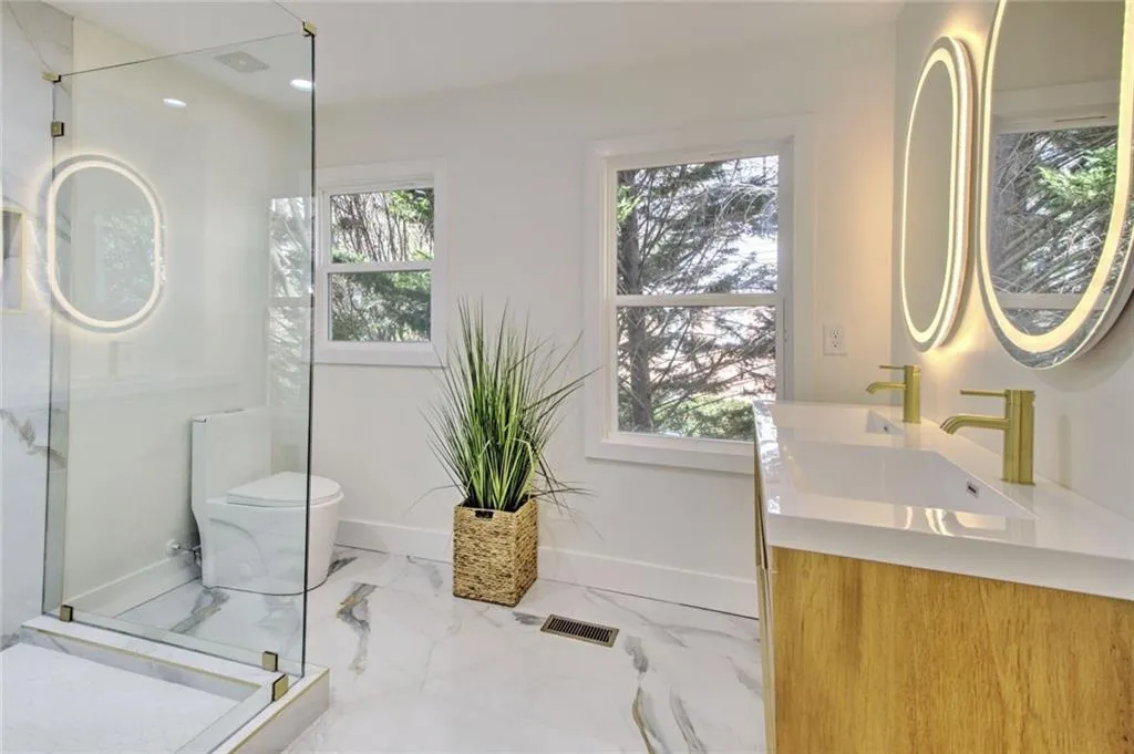 Bathroom with a marble finish shower, double vanity, light marble finish flooring, and recessed lighting