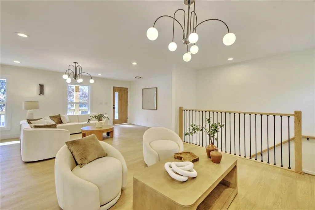 Living room with a chandelier, light wood-style floors, and recessed lighting