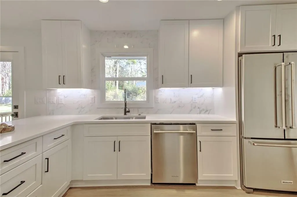 Kitchen with stainless steel appliances, decorative backsplash, white cabinetry, light stone countertops, and recessed lighting