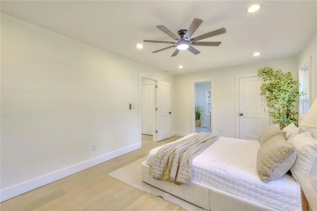 Bedroom with light wood finished floors, ceiling fan, recessed lighting, and ensuite bath