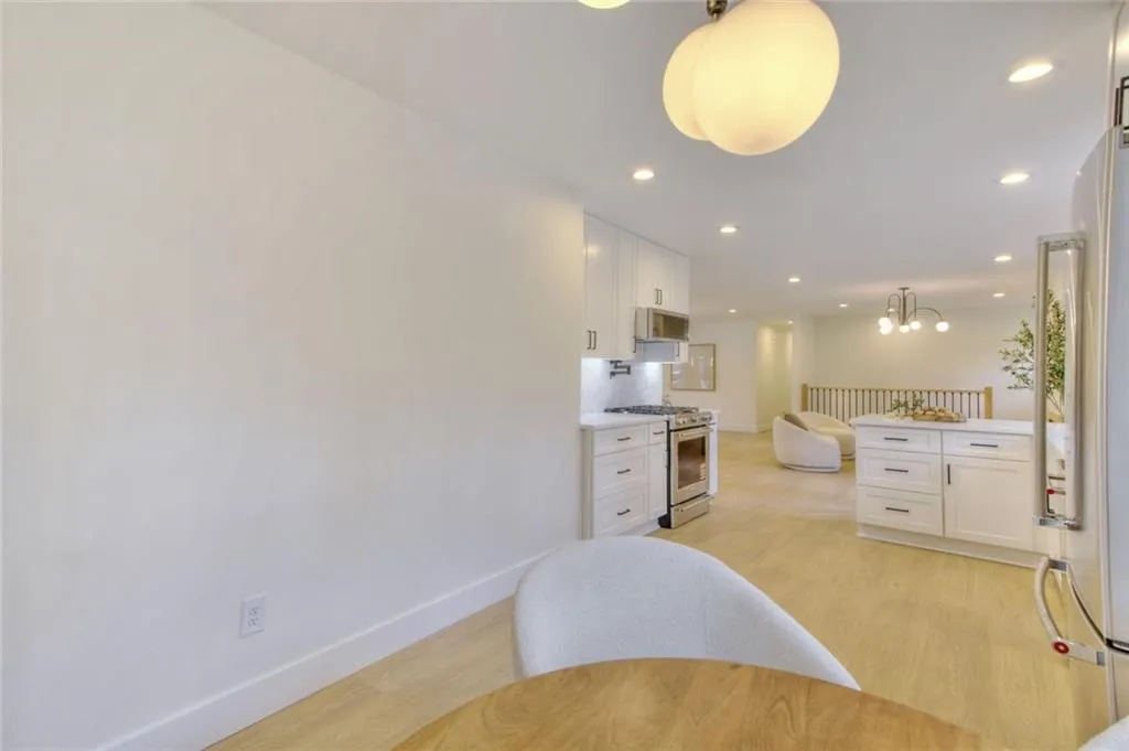 Kitchen with white cabinetry, decorative light fixtures, recessed lighting, stainless steel appliances, and light wood-style floors