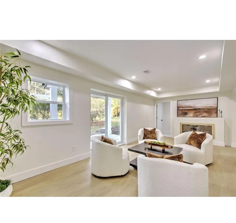 Living room featuring a glass covered fireplace, recessed lighting, light wood-style floors, and a tray ceiling